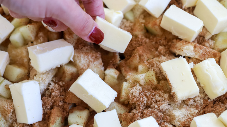 Butter cubes being added over a brown sugar cinnamon mixture