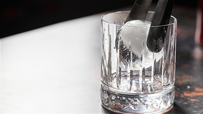 tongs adding ice to glass