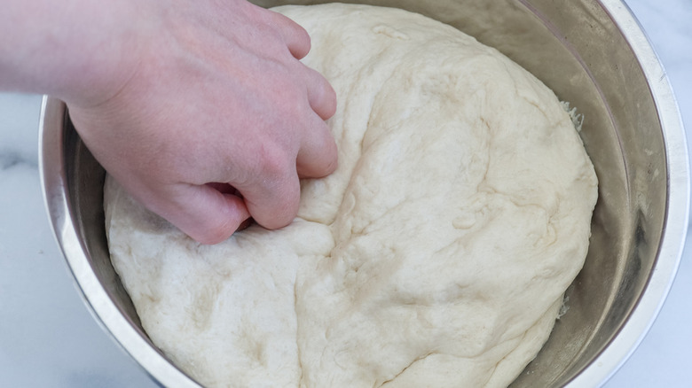 hand punching dough in bowl
