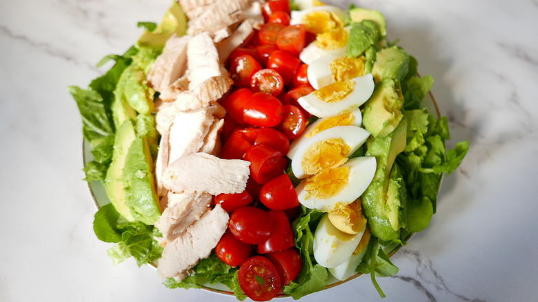 assembling Cobb salad in bowl