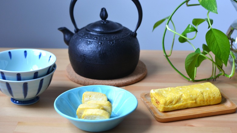 sliced tamagoyaki in blue bowl with tea pot