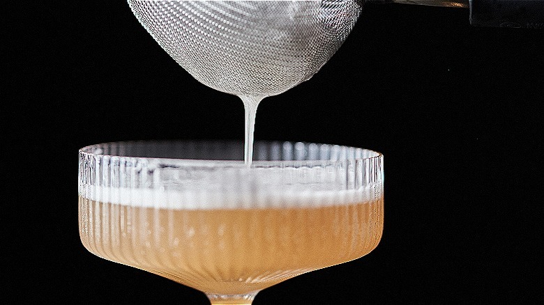 straining cocktail into glass