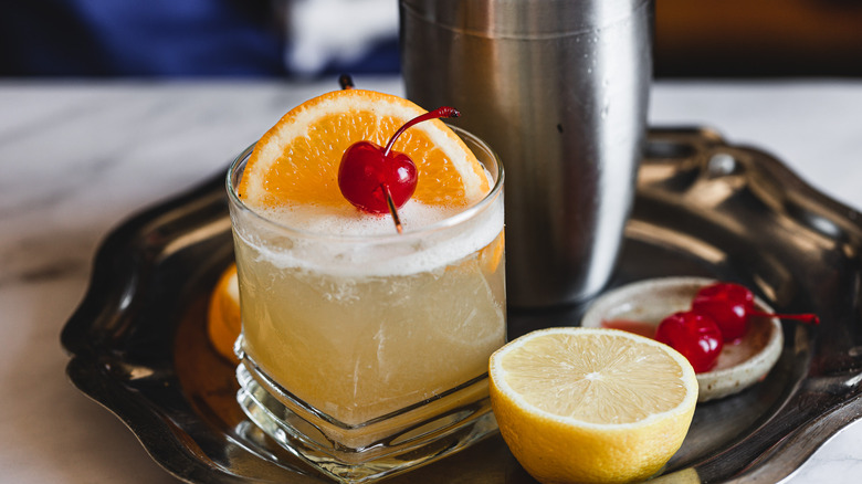 whiskey sour on a metal tray with garnishes