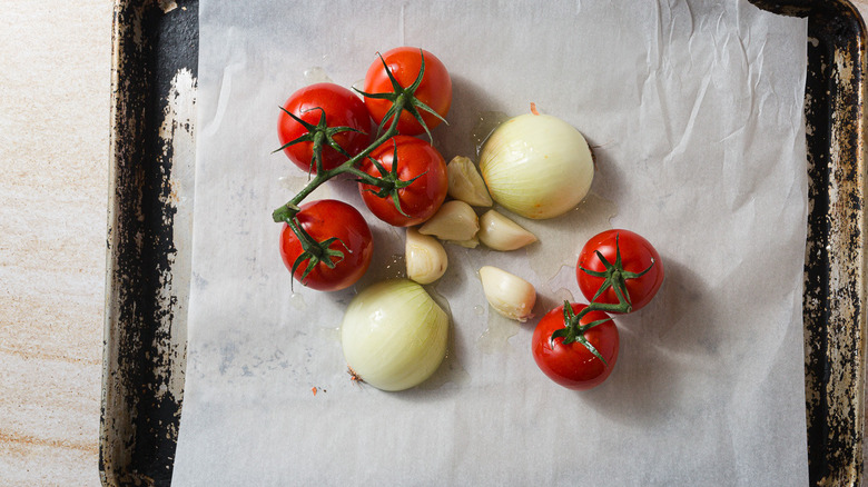 Tomatoes, onions and garlic on baking sheet