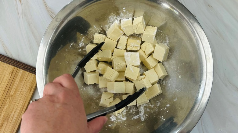 hand stirring tofu in bowl