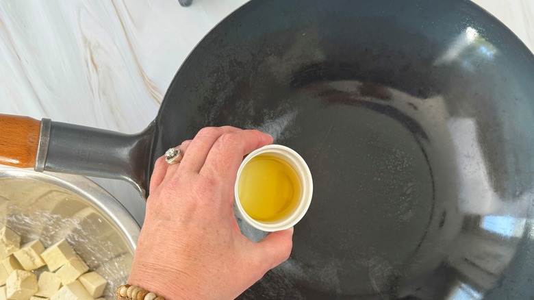 hand pouring oil in pan