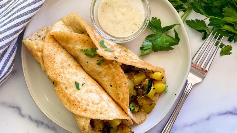 masala dosa on plate with fork and dipping sauce