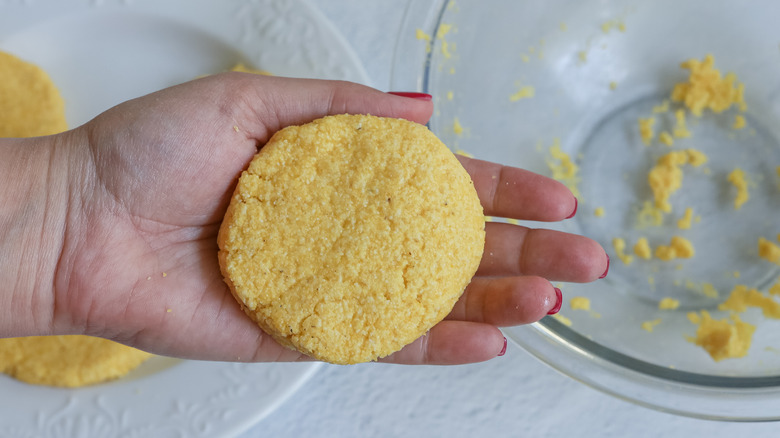 uncooked corn pone in hand