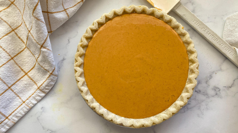 unbaked pumpkin pie with towel