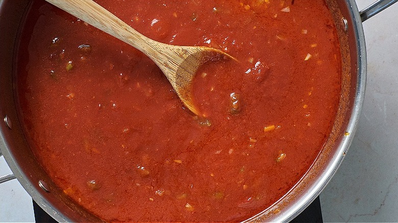 stirring tomato sauce in skillet