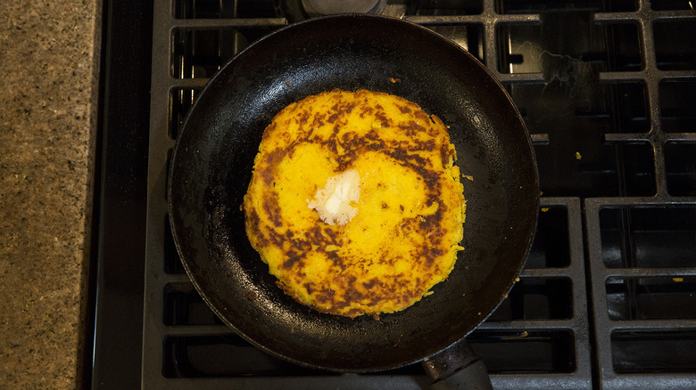 buttered cachapa in frying pan