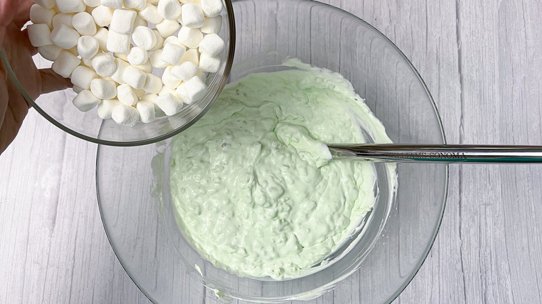 pouring marshmallows into green pudding