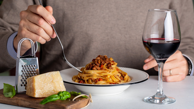 eating bolognese pasta with red wine