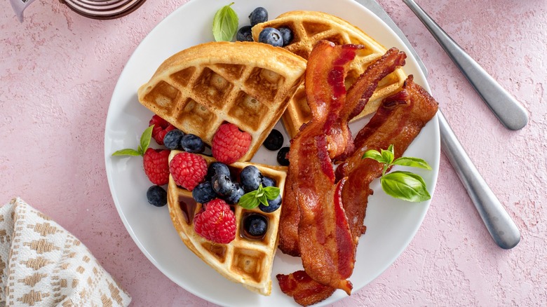 Top-down view of berries, waffles, and bacon on a plate