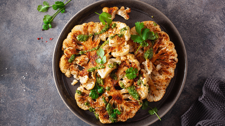 roasted cauliflower steaks on a dark plate