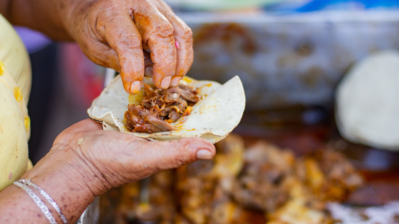 woman garnishing cochinita pibil