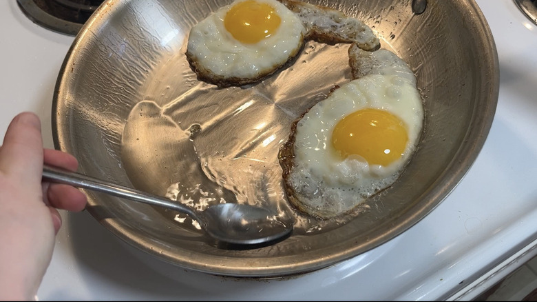 spooning oil over fried eggs