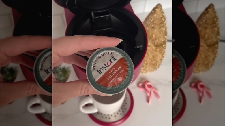 A woman holding an Instant coffee pod