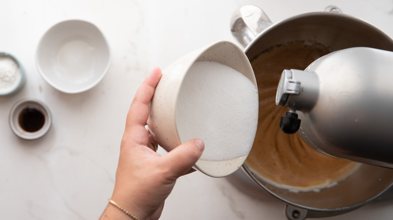 Hand adding sugar to bowl