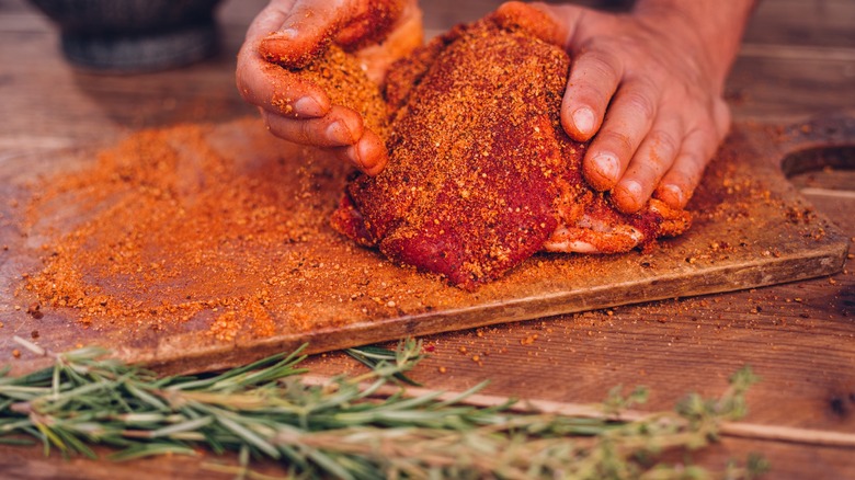 Person applying dry rub to raw pork