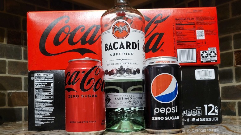 Coke and pepsi zero cans with a bottle of bacardi