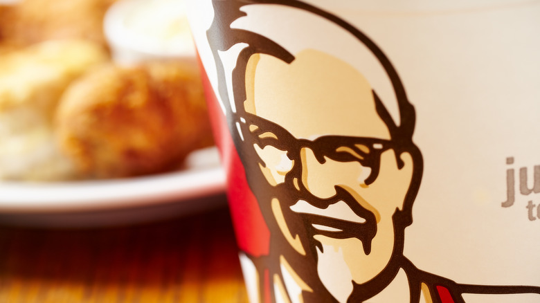 Close-up of Colonel Sanders on a KFC bucket in front of plated food