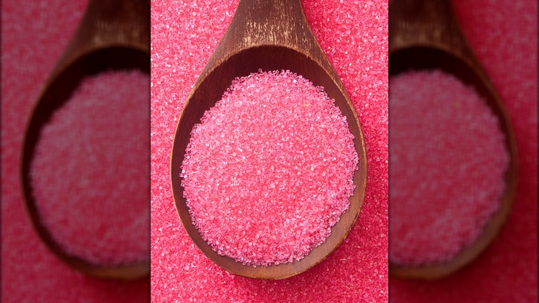 Wooden spoon full of pink sugar