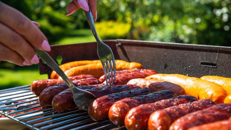 forks moving hotdogs on a grill