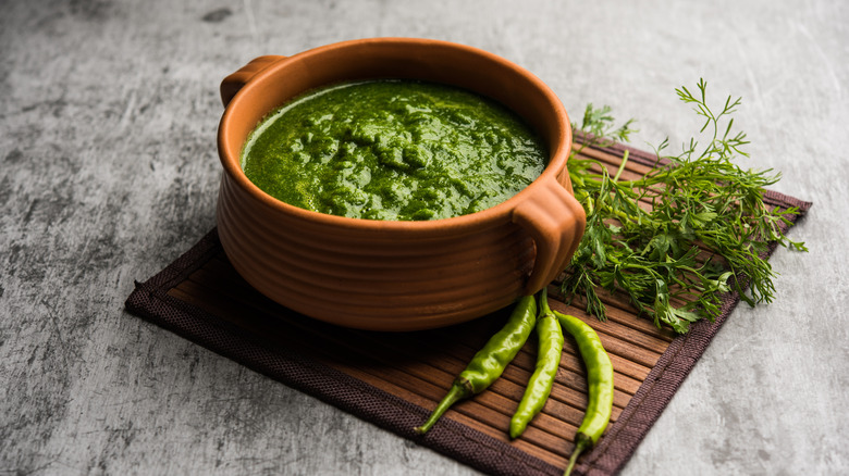 Green chutney next to chilis and cilantro