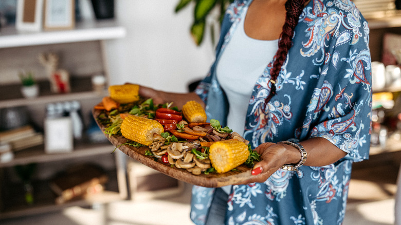 person carrying a platter with stacked food