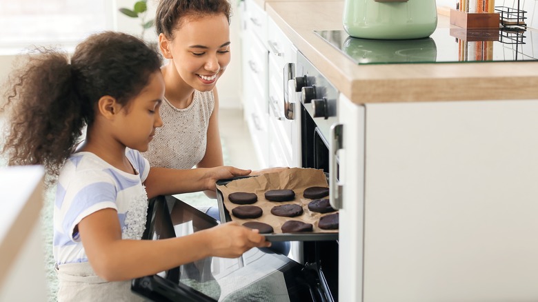 Family putting cookies in oven