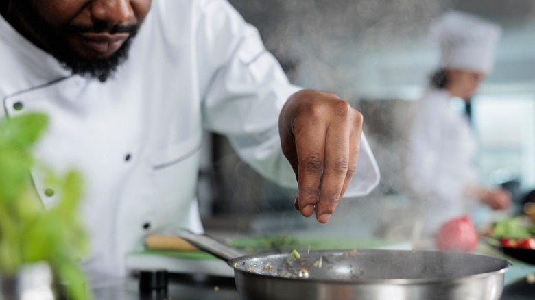 A chef cooking chopped vegetables