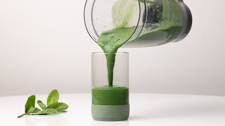 pouring green smoothie into glass