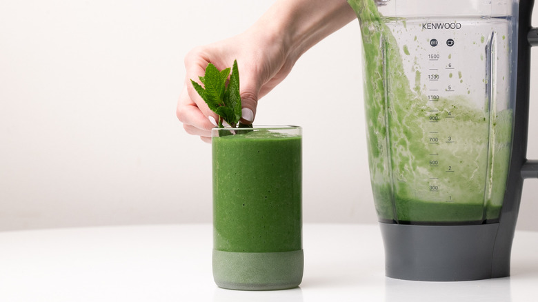 garnishing green smoothie with mint