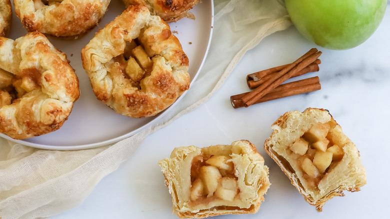 apple-filled pastries with cinnamon sticks and an apple