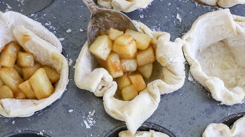 spoon putting apple filling into a dough cup