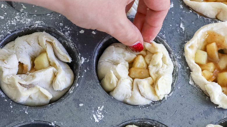 hand folding dough over apple filling