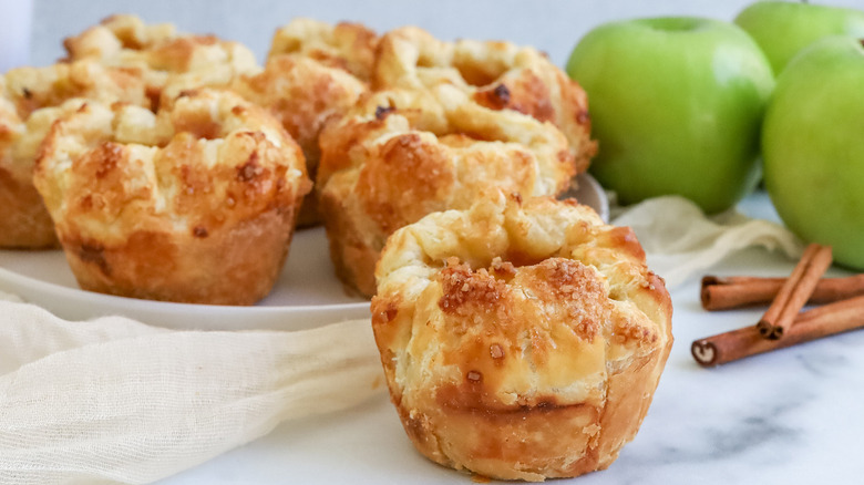 muffin-shaped pastries with cinnamon sticks and apples