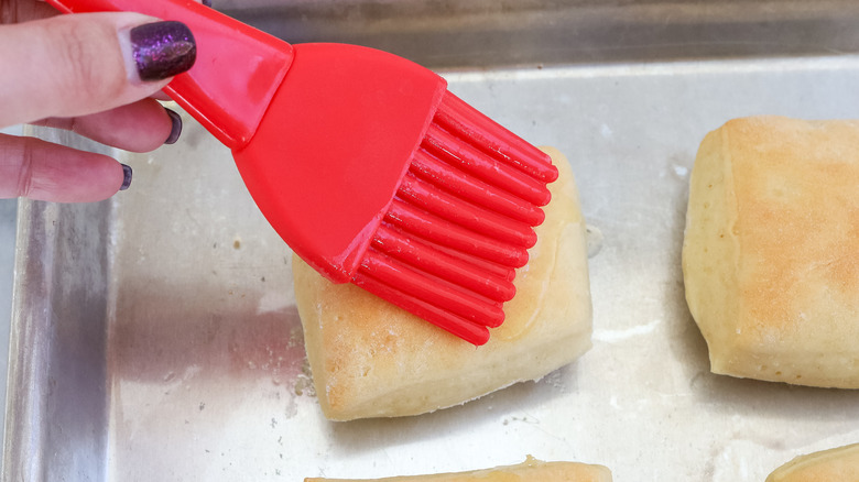 Hand brushing baked rolls with butter