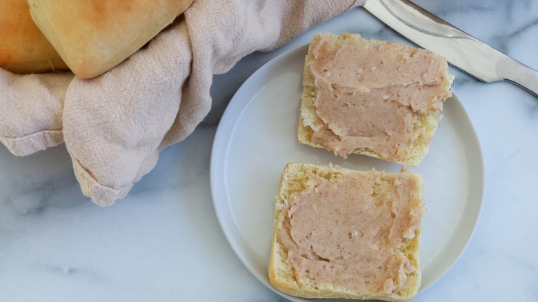 A cut-up roll on a plate spread with butter