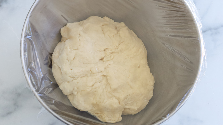 Dough in a bowl covered with plastic wrap