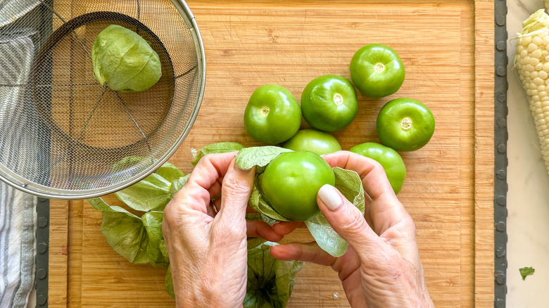 hand removing husks from tomatillo