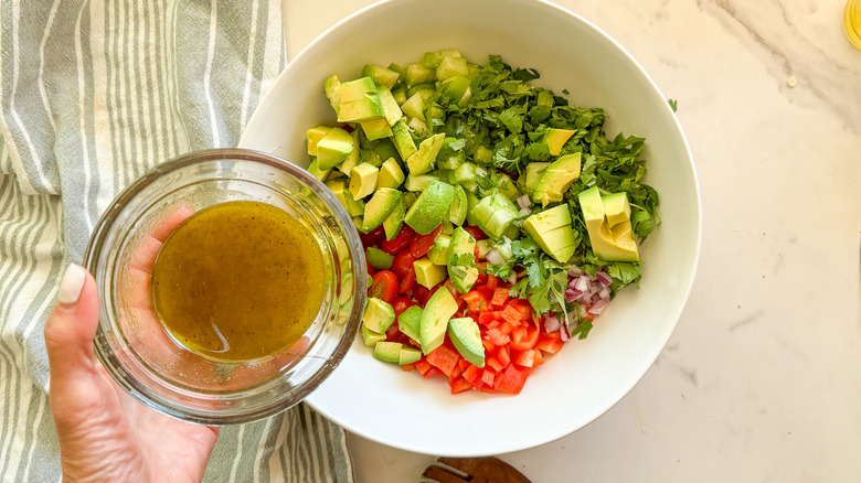 hand adding dressing to bowl