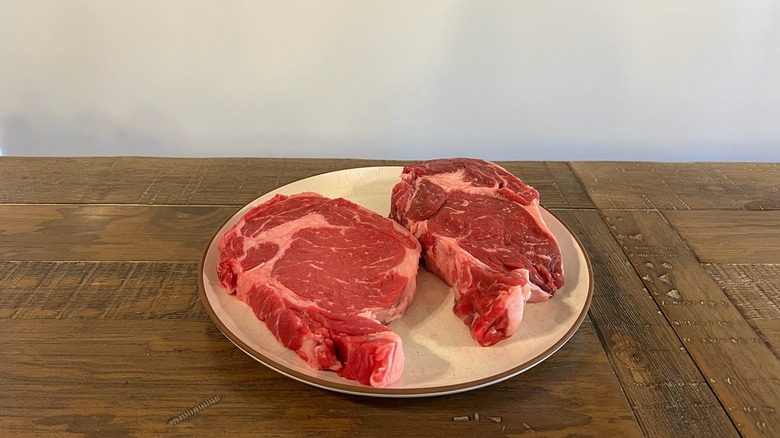 two raw cuts of ribeye steak on table