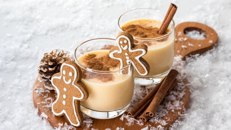 Glasses of eggnog garnished with gingerbread men and cinnamon sticks