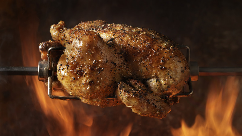 A rotisserie chicken cooking over a fire