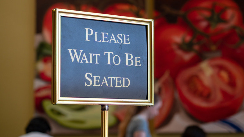 please wait to be seated sign at restaurant