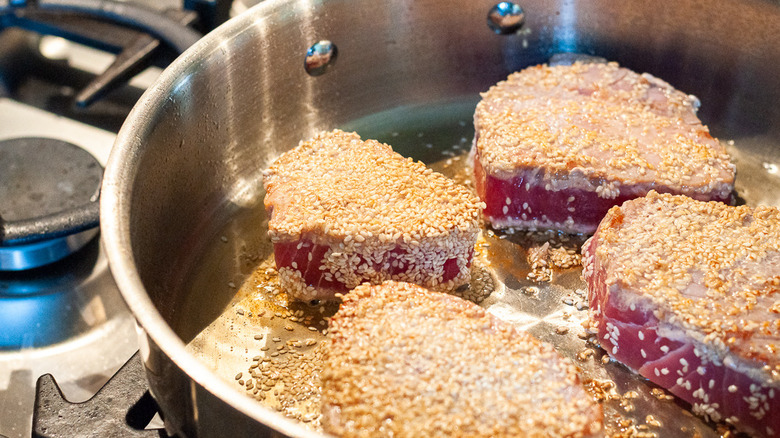 Sesame-crusted tuna steaks in pot