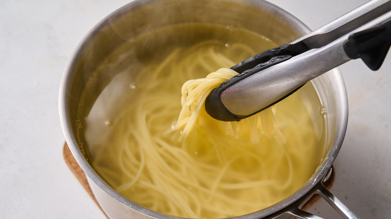 removing boiling pasta from water in pot