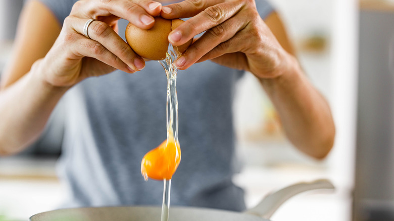 hand cracking an egg in a pan